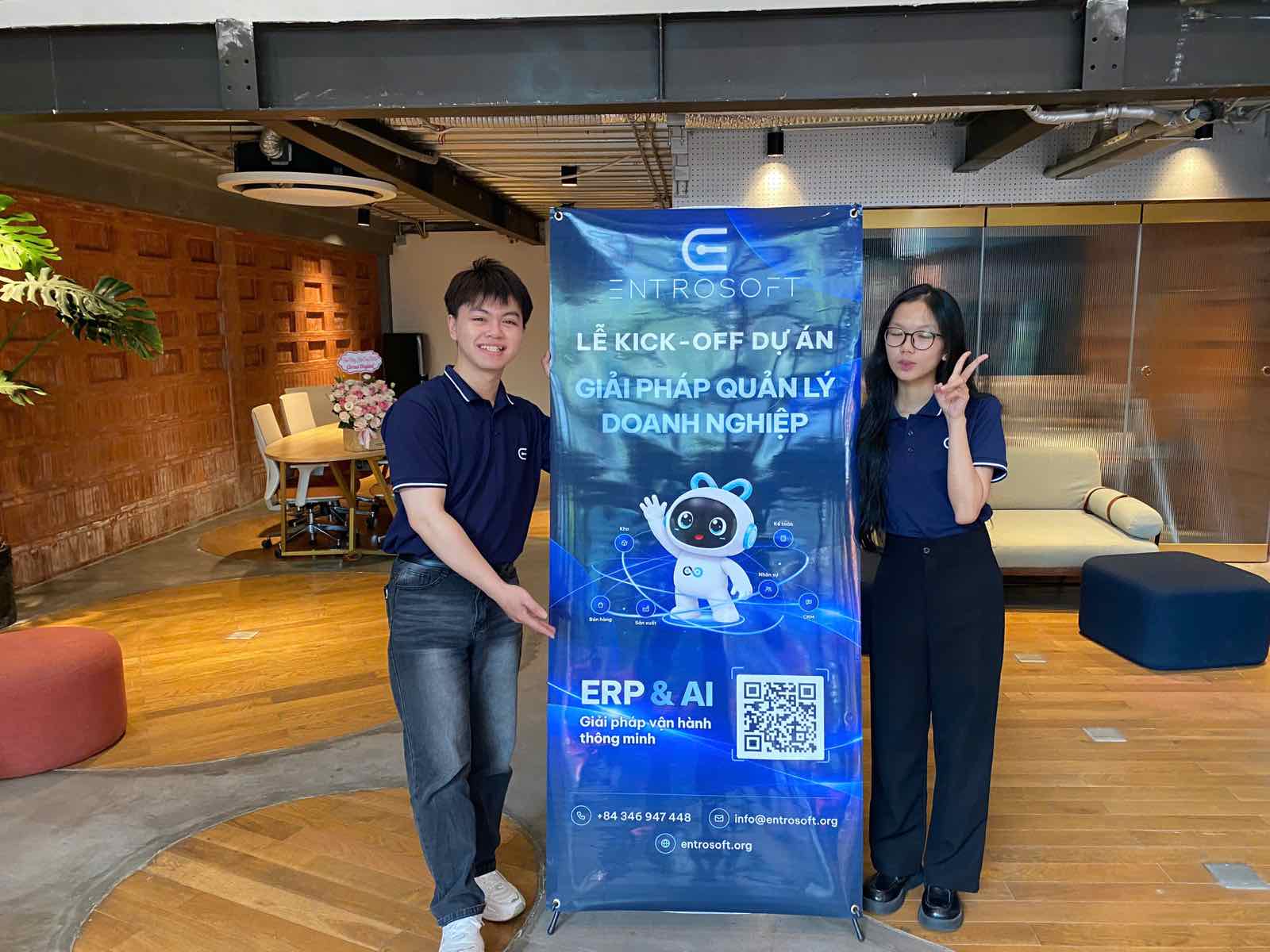 Two ENTROSOFT representatives beside the project kick-off standee