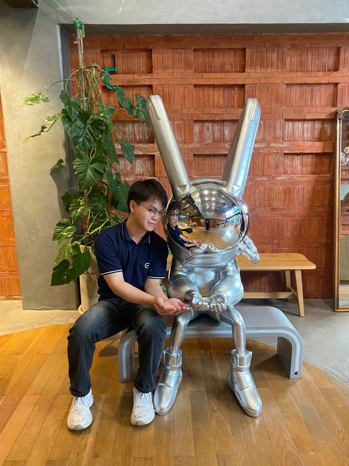 An ENTROSOFT team member sitting next to the silver rabbit statue in the lobby